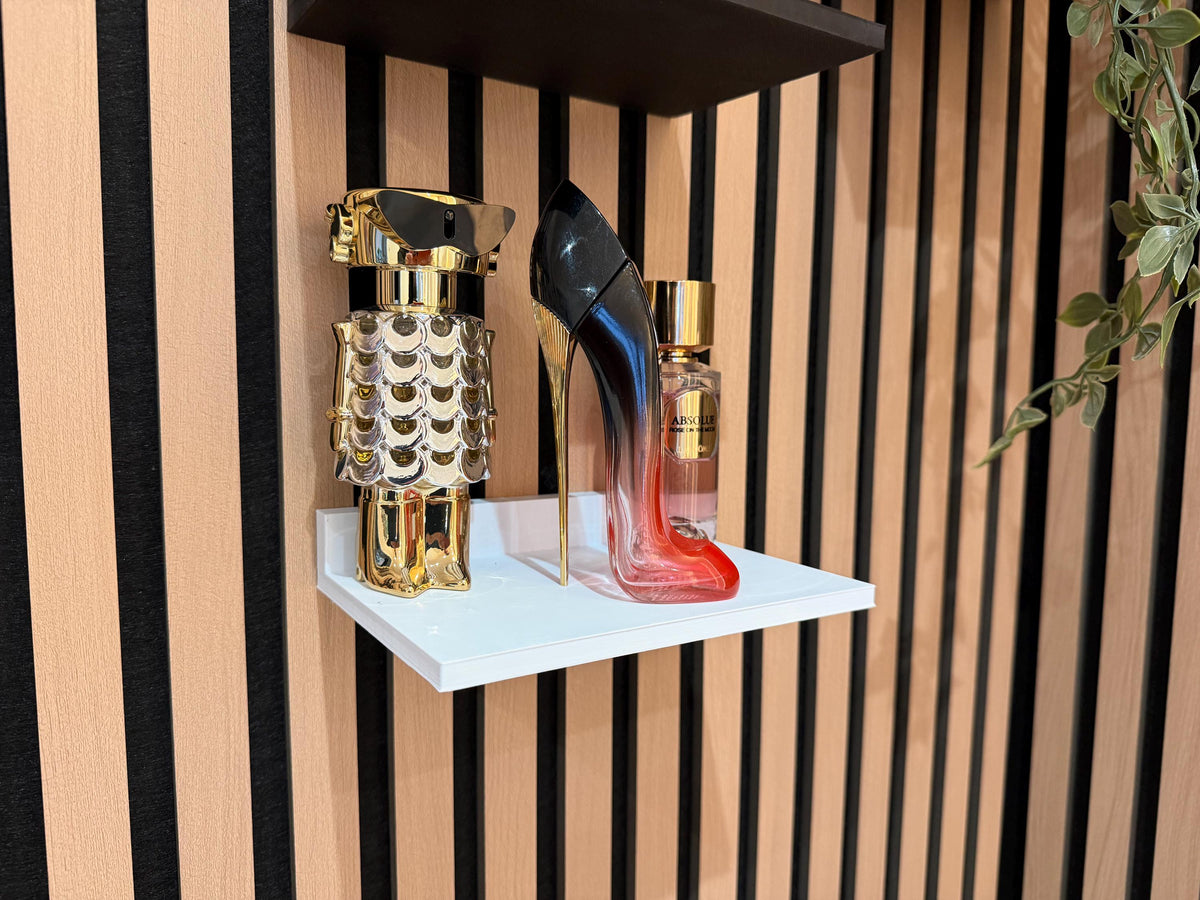 White perfume shelf on a slat wall displaying two decorative perfume bottles, wider angle
