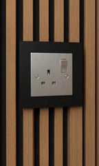 Chrome single-gang socket surround fitted over a UK socket on an acoustic slat wall panel