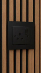 Black single-gang socket surround fitted over a UK socket on an acoustic slat wall panel