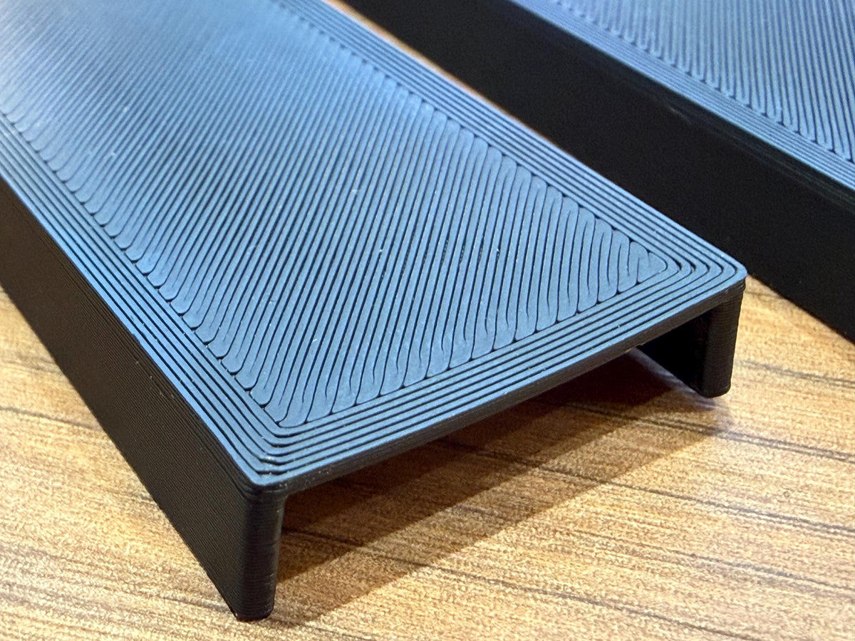 Single black acoustic panel decorative cover on a wood surface, close-up
