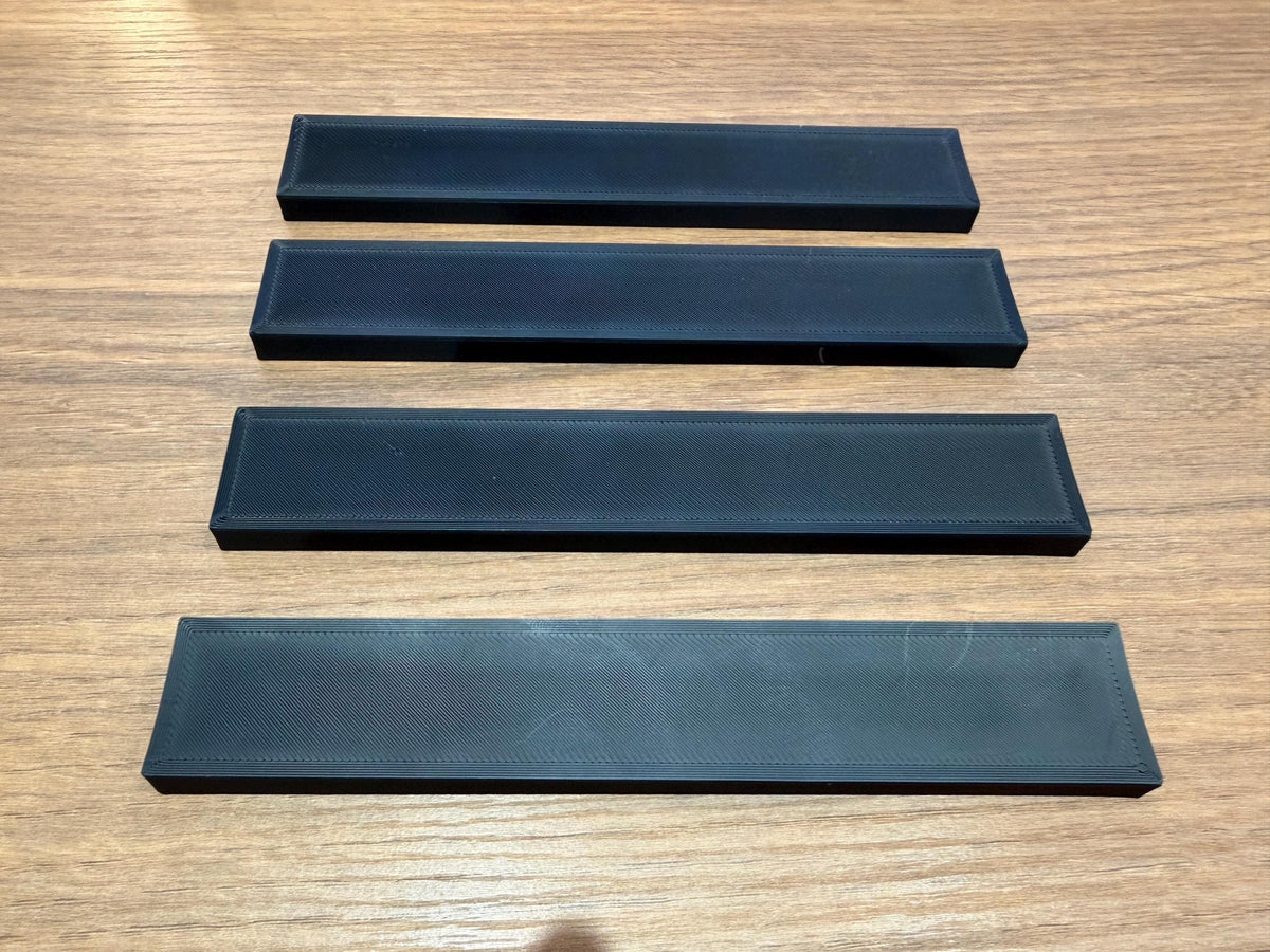 Four black acoustic panel decorative covers laid flat on a wood surface