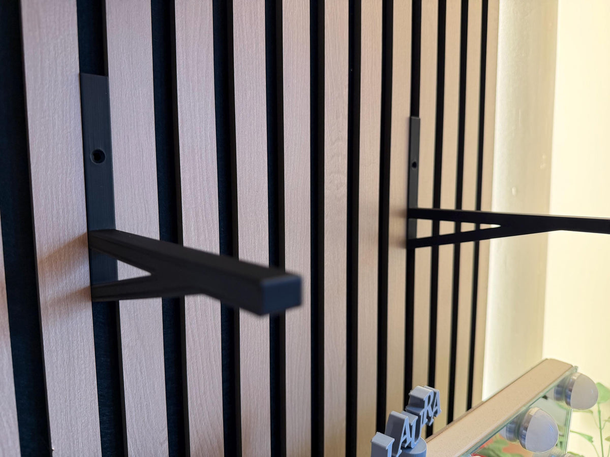 Black shelf bracket clipped onto an acoustic slat wall panel, side view
