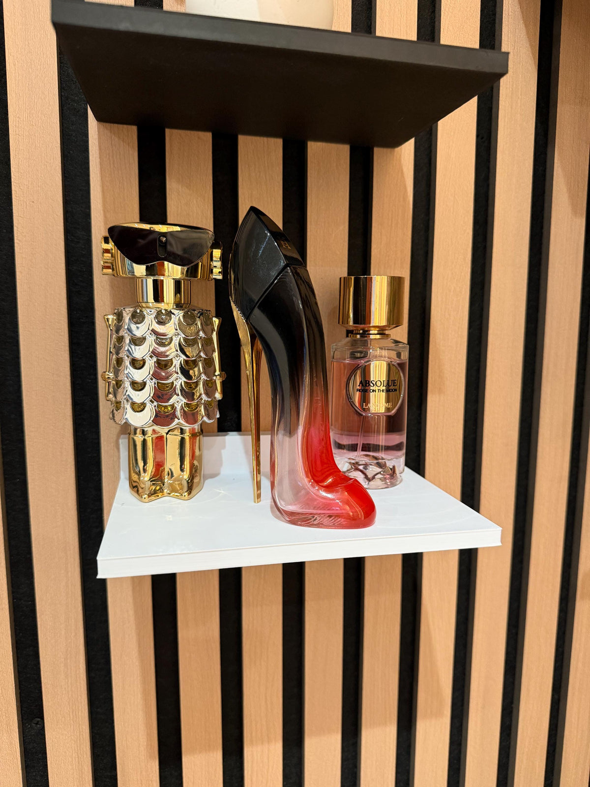 White perfume shelf on a slat wall displaying fragrance bottles, front view