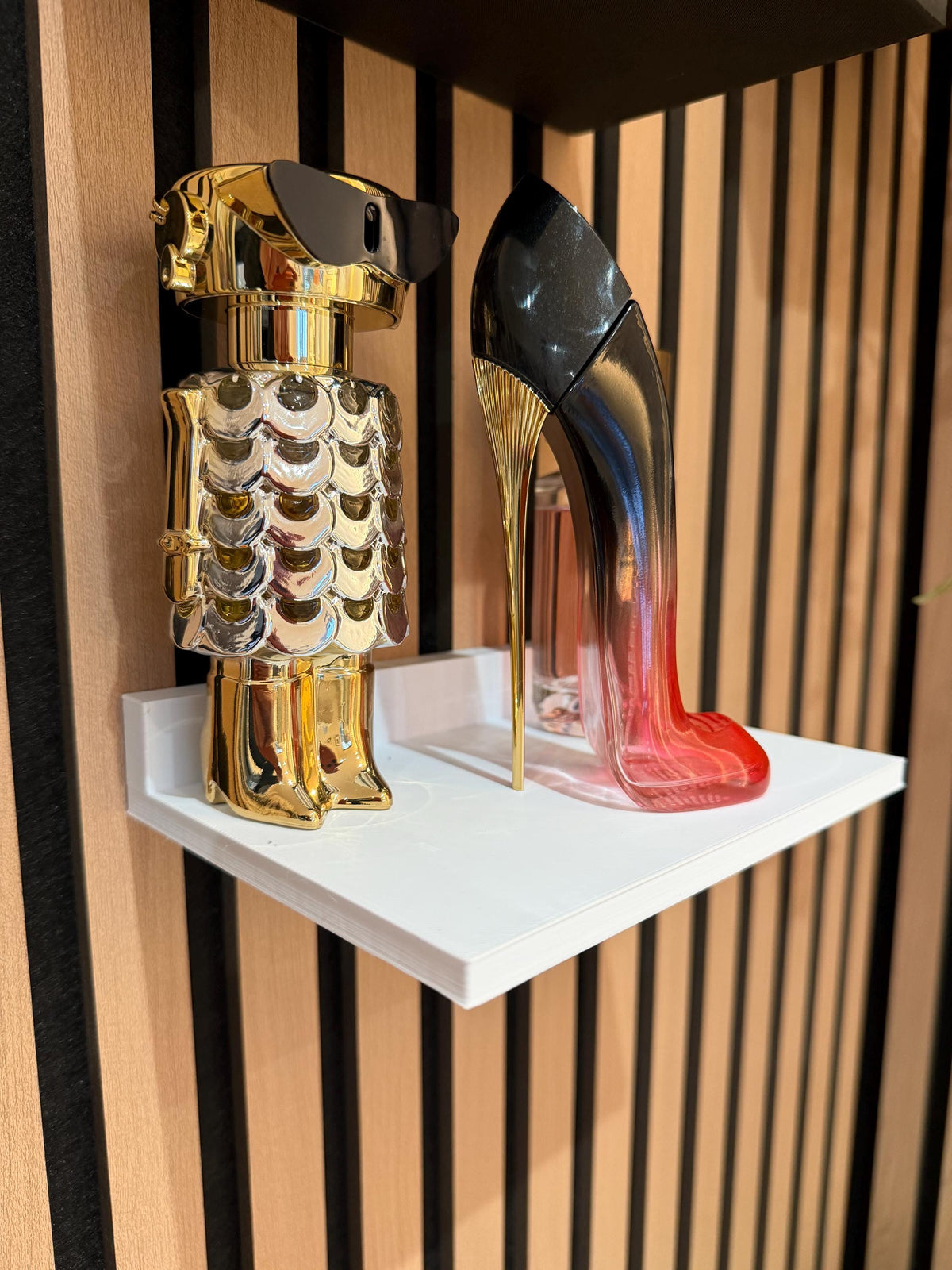 White perfume shelf on a slat wall displaying two decorative perfume bottles