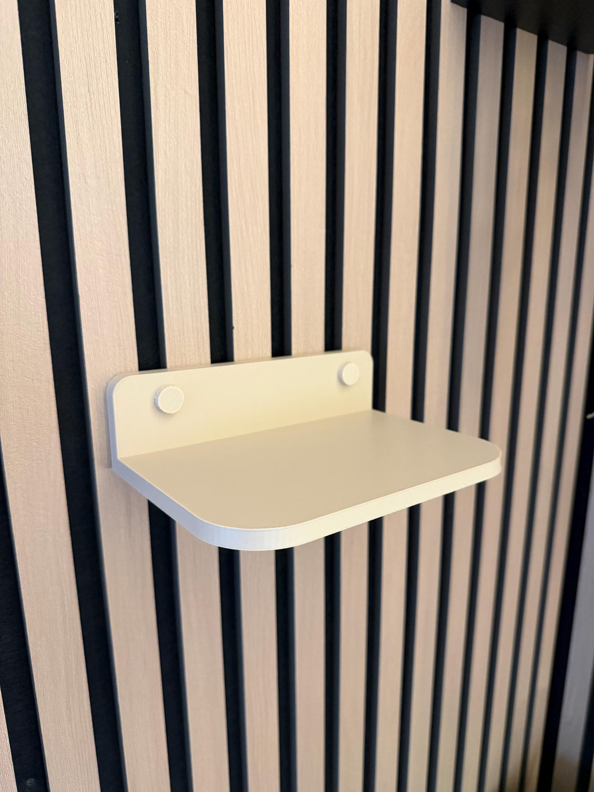Beige floating shelf clipped onto an acoustic slat wall panel, empty