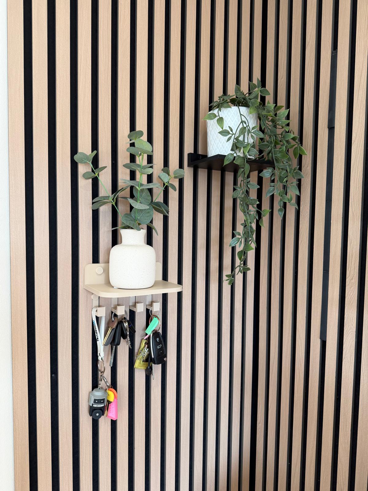 Key holder shelf on a slat wall styled with a plant, vase and hanging keys, wider angle