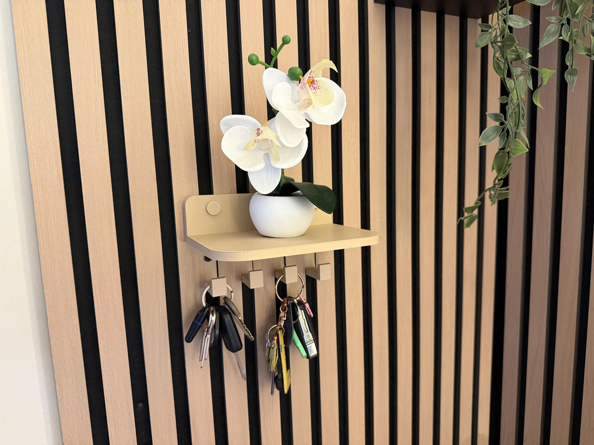 Key holder shelf on a slat wall styled with an orchid and hanging keys, close-up