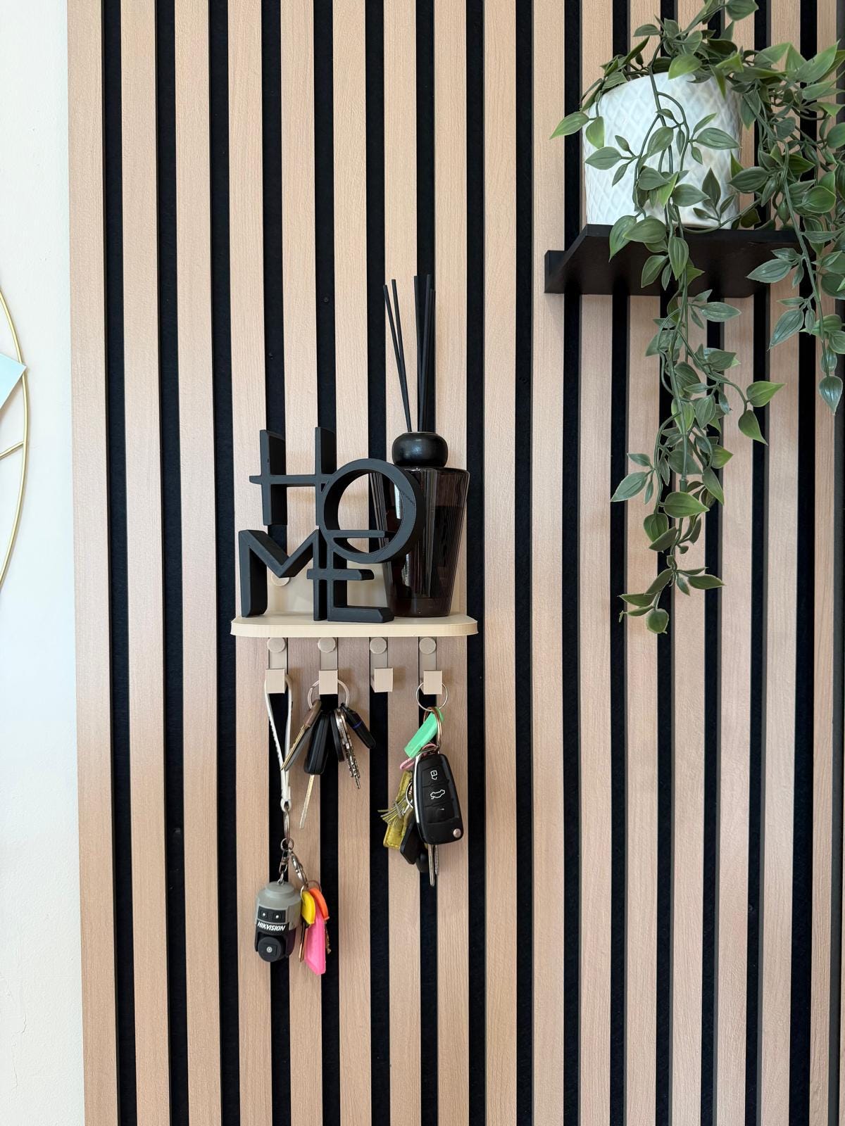 Key holder shelf on a slat wall styled with a plant and hanging keys, alternate styling