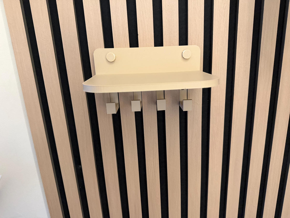 Empty beige key holder shelf mounted on an acoustic slat wall panel
