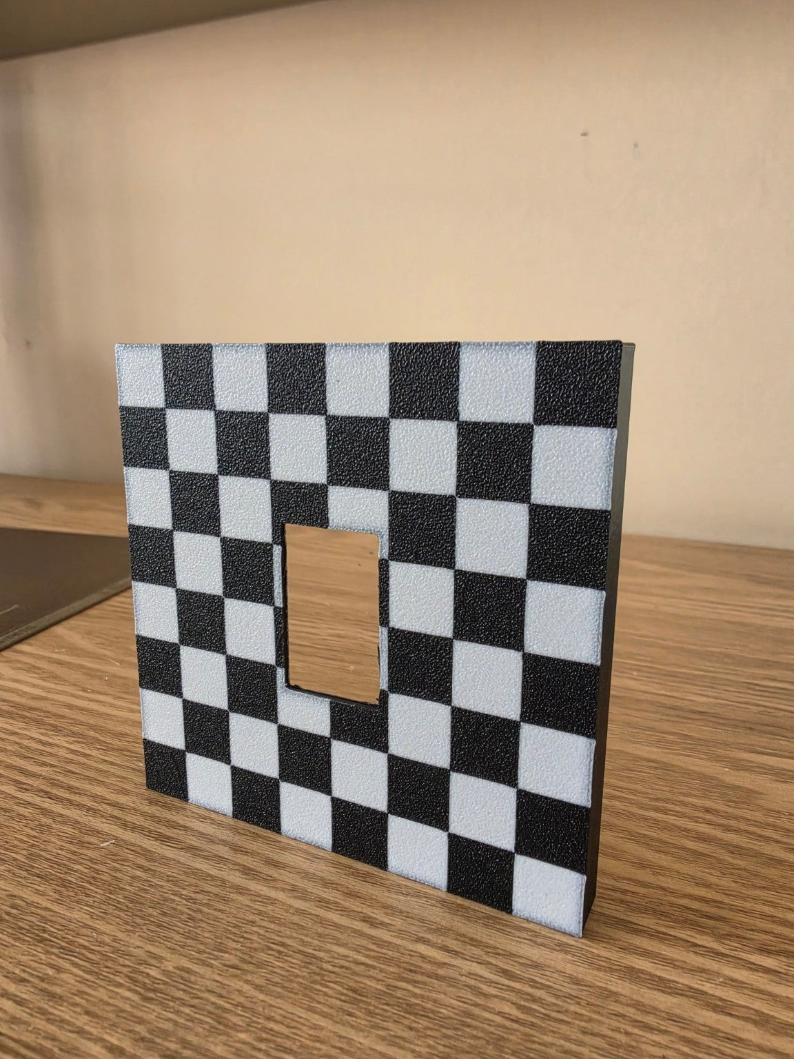 Checkerboard switch surround fitted around a light switch